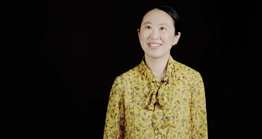 A Te Pūaha Talk attendee wearing a yellow floral top, smiles warmly at the camera.
