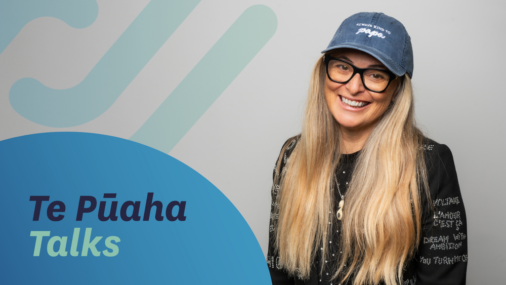 Centre for Social Impact Associate Tuihana Ohia smiles at the camera, wearing a decorated jacket and denim cap. Text reads ‘Te Pūaha Talks.’